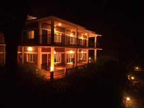 A two-story building with a balcony on the upper floor, surrounded by vegetation. - Forestdale Coorg (Virajpet)
