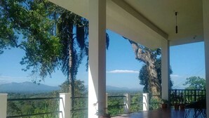A covered outdoor area with a view of mountains and trees. - Forestdale Coorg (Virajpet)