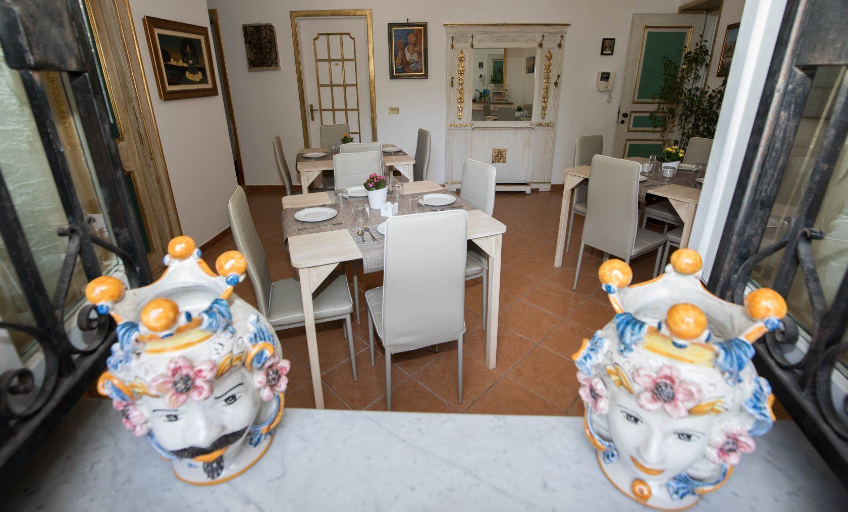 A dining area with multiple tables and chairs, a mirror, and a decorative ceramic piece on the table.