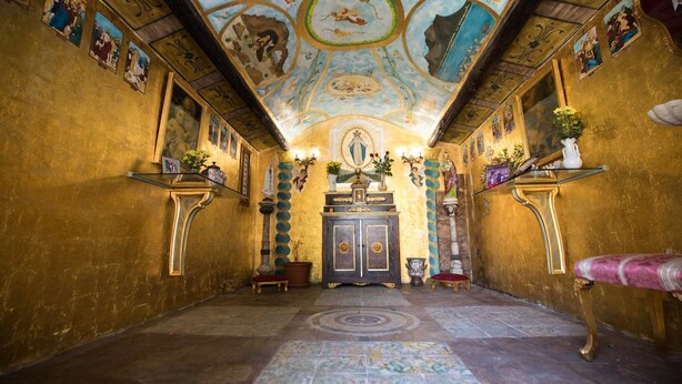 A chapel with a golden interior, a wooden altar, and religious paintings on the walls. - Cannatella's Mansion (Palermo)