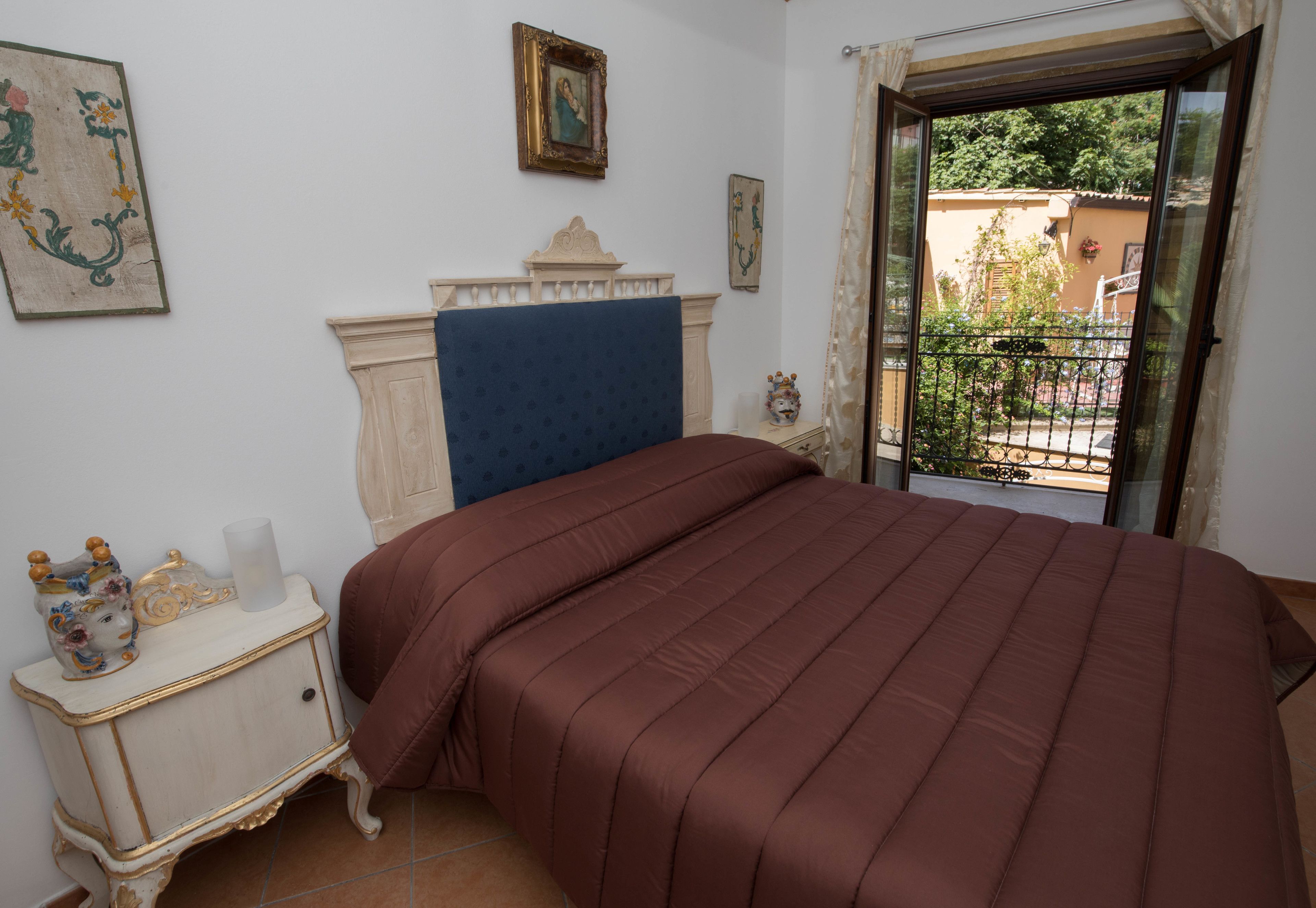 A bedroom with a large bed, a dresser, and a window with a view of a balcony.