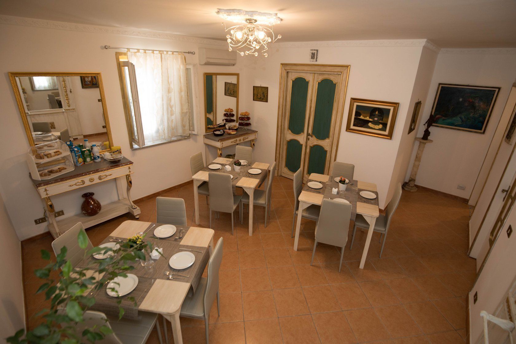 Un coin repas agrémenté d’un lustre, d’un miroir et d’une table à manger dressée pour quatre personnes.