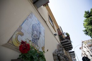 A building with a mosaic mural, a balcony with plants, and a statue. - Cannatella's Mansion (Palermo)