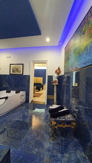 A modern bathroom with a marble floor, a bathtub, and a vanity with a mirror. - Cannatella's Mansion (Palermo)