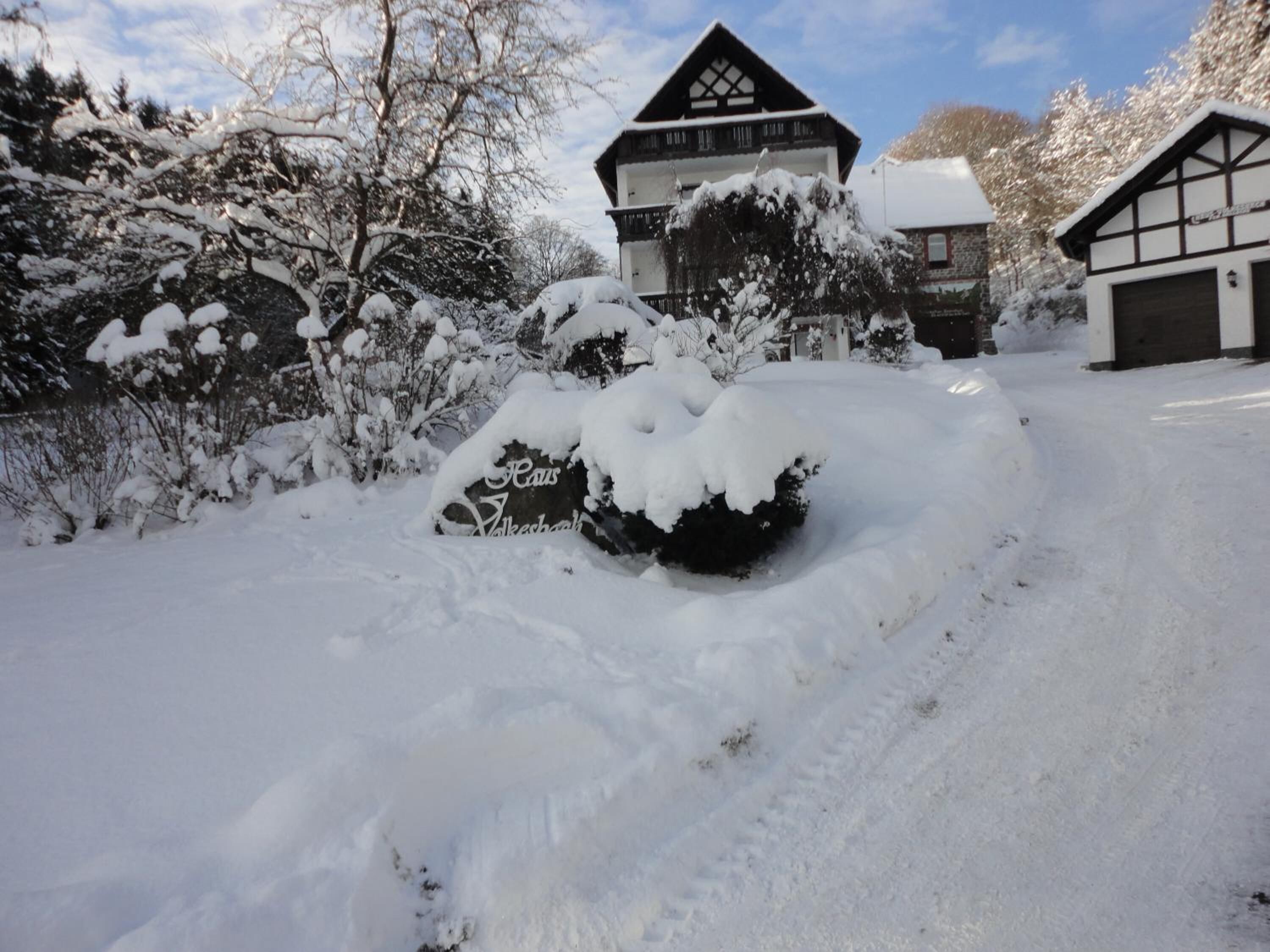 A snow-covered landscape with a house and garage.
