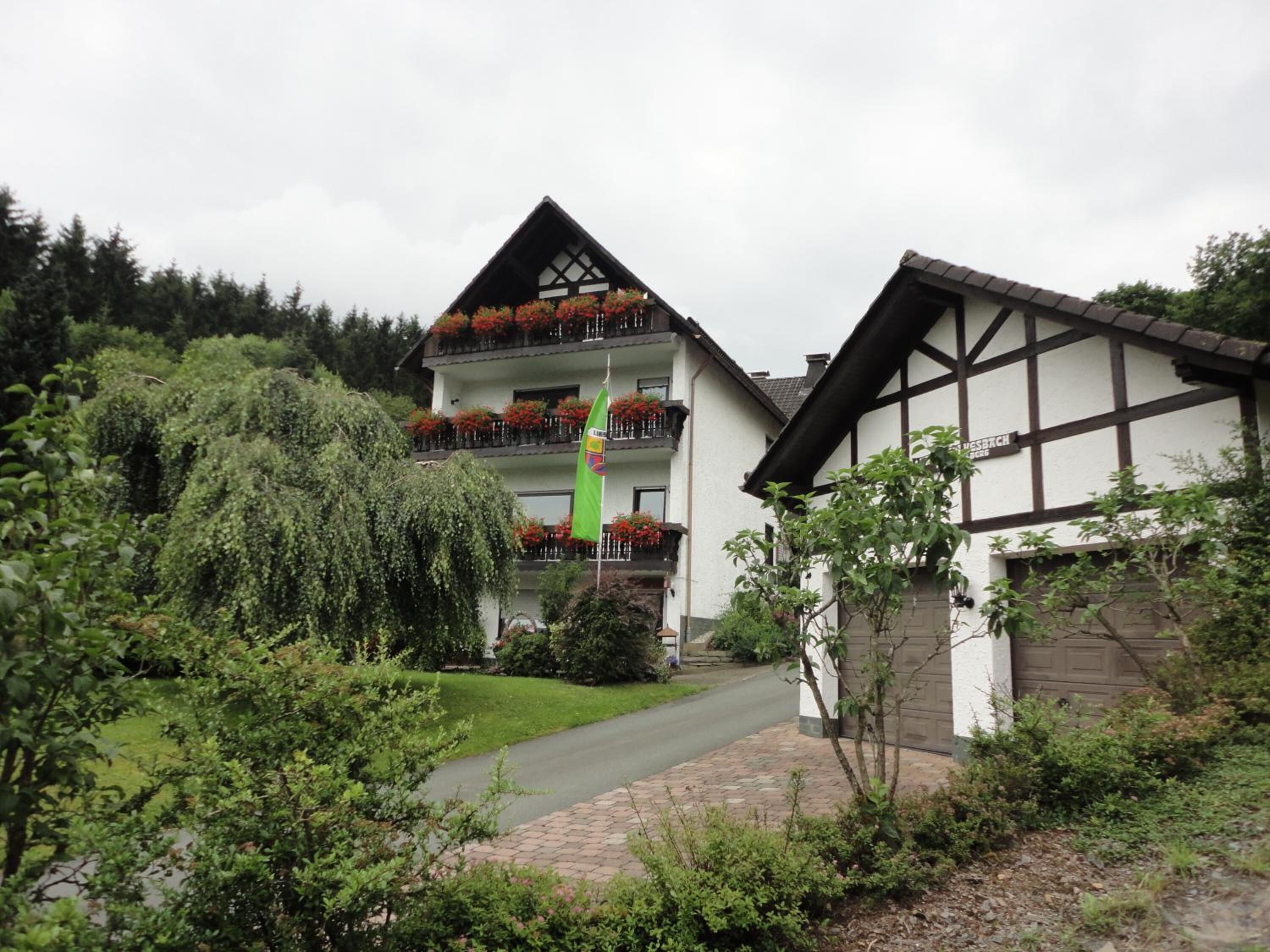 Un bâtiment à deux étages, doté d’un balcon à l’étage supérieur et entouré de verdure.