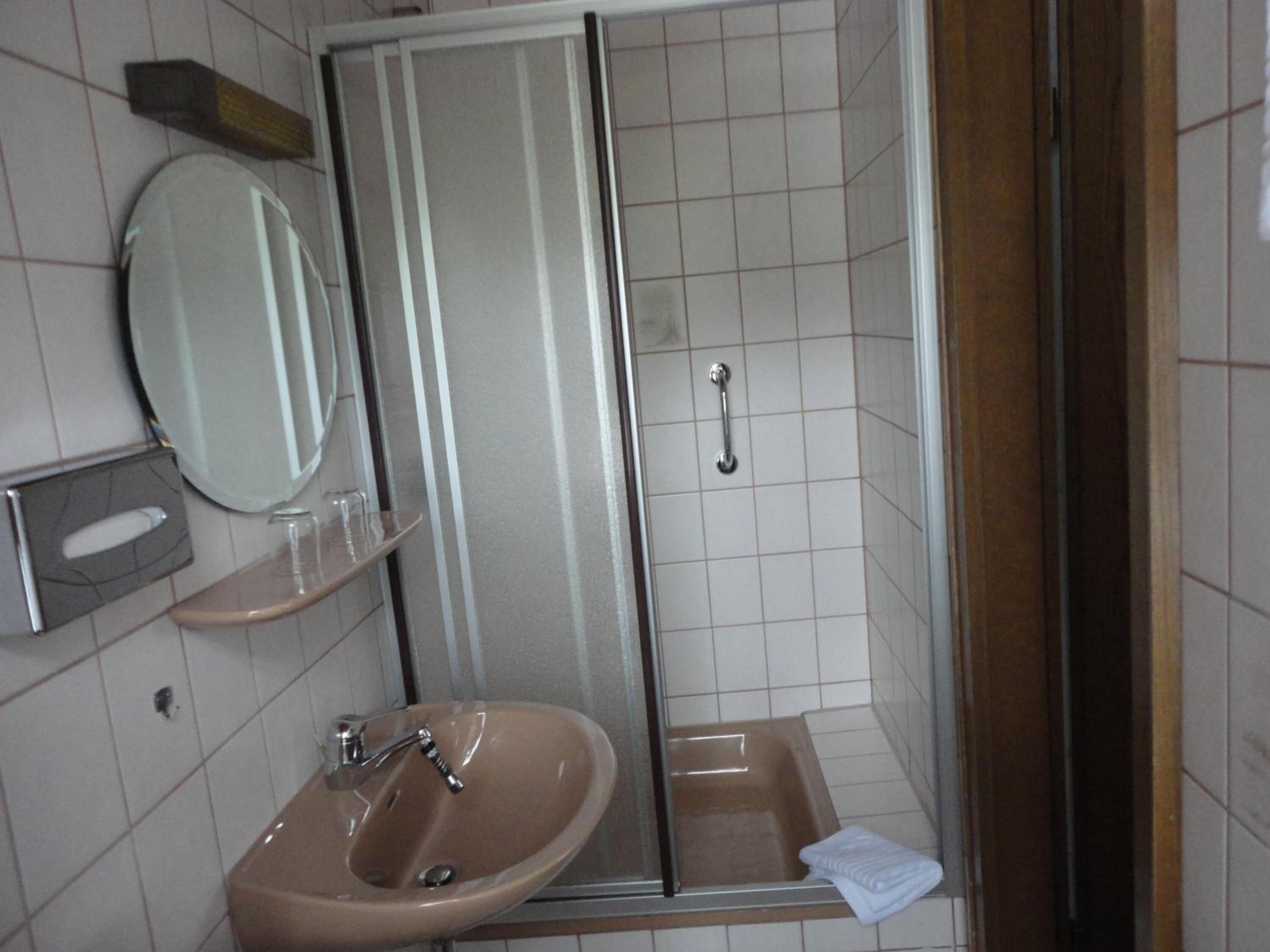 Un baño con lavamanos, espejo y ducha.