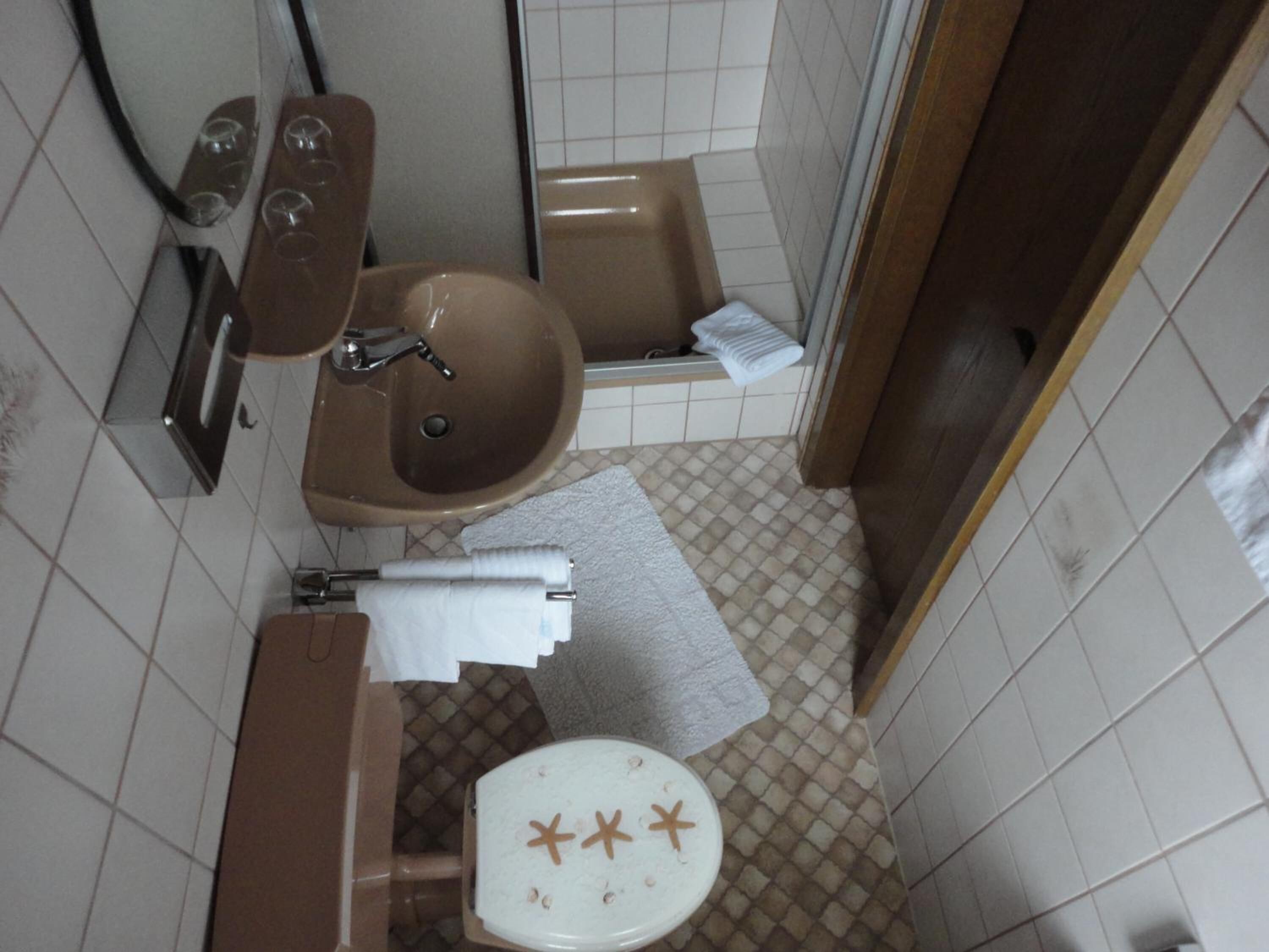 Een kleine badkamer met toilet, wastafel en bad.