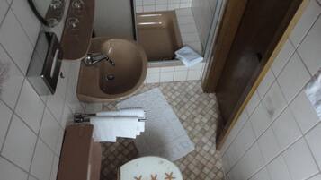 Een kleine badkamer met toilet, wastafel en bad.