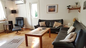 A living room with a sofa, a chair, a coffee table, and a radiator.