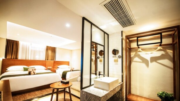 A hotel room with a bed, bedside table, mirror, and a built-in wardrobe.