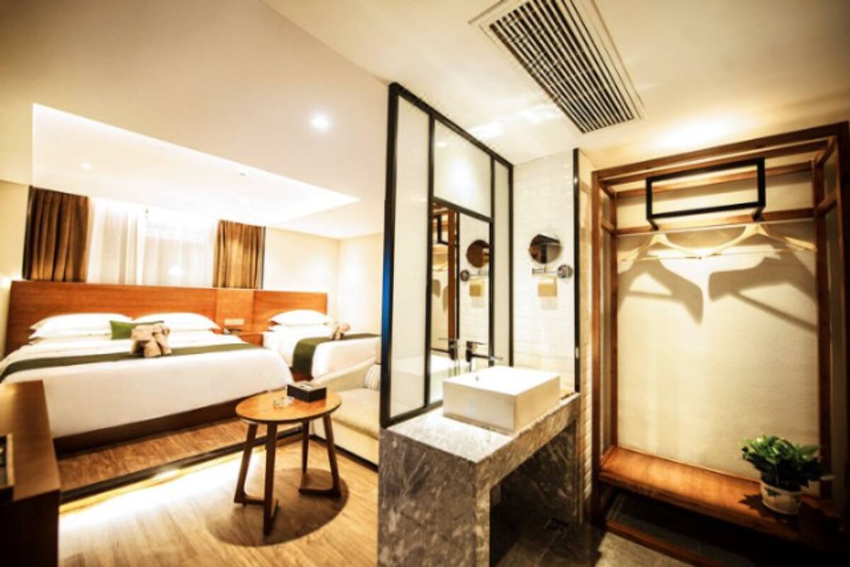 Habitación de hotel con cama, mesita de noche, espejo y armario empotrado.
