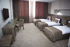A hotel room with two beds, a desk, a chair, a TV, and a large window with curtains.