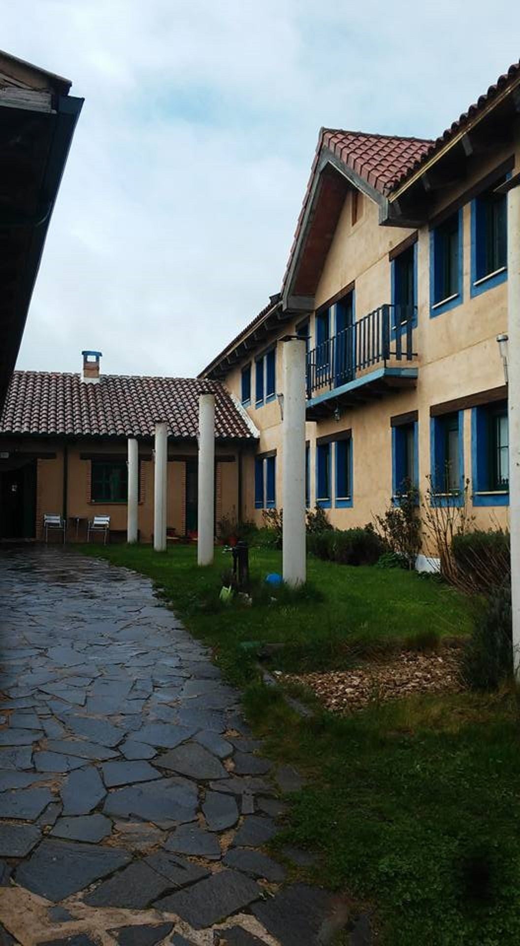 A courtyard with a stone pathway leading to a building with a tiled roof and columns.
