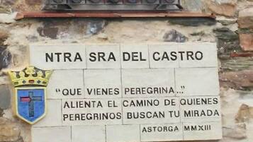 Un muro de piedra con una estatua religiosa y una placa con texto.