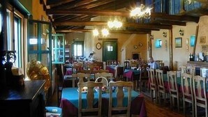 A cozy restaurant with wooden beams, tables with blue tablecloths, and chairs. - Hostería Casa Flor (Astorga)