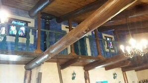 A room with exposed wooden beams, a balcony with a railing, and a chandelier. - Hostería Casa Flor (Astorga)