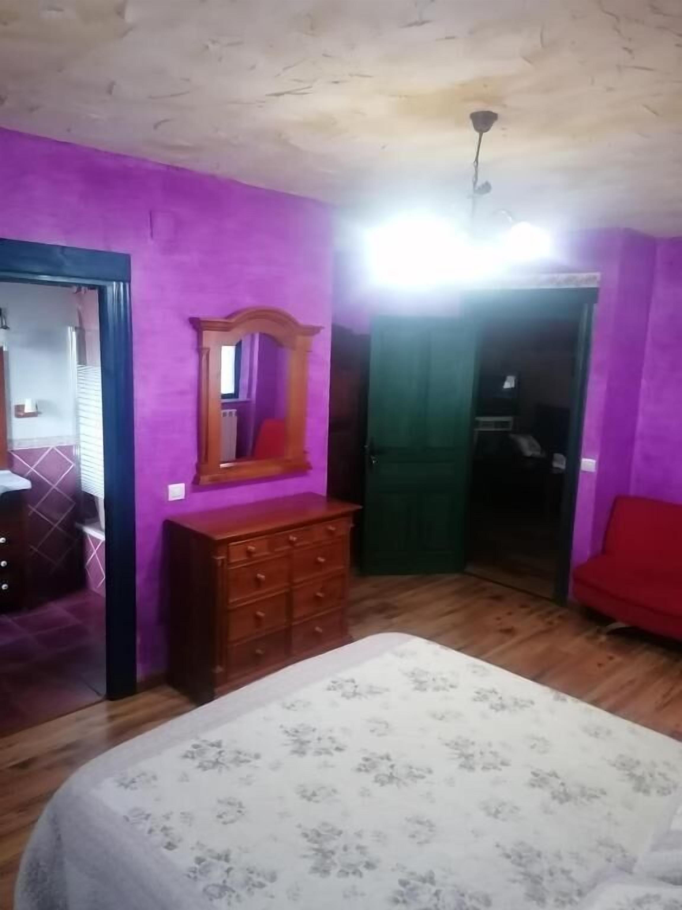 A bedroom with a bed, dresser, and a mirror.