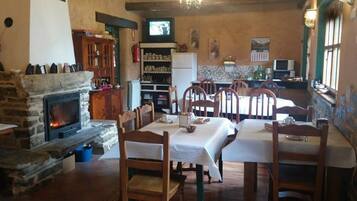 A cozy dining area with a fireplace, wooden chairs, and a table set for a meal.