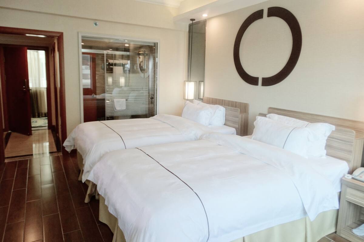 A hotel room with two beds, a large mirror, and a circular wall decoration.