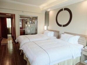 Habitación de hotel con dos camas, un espejo grande y un adorno circular en la pared.