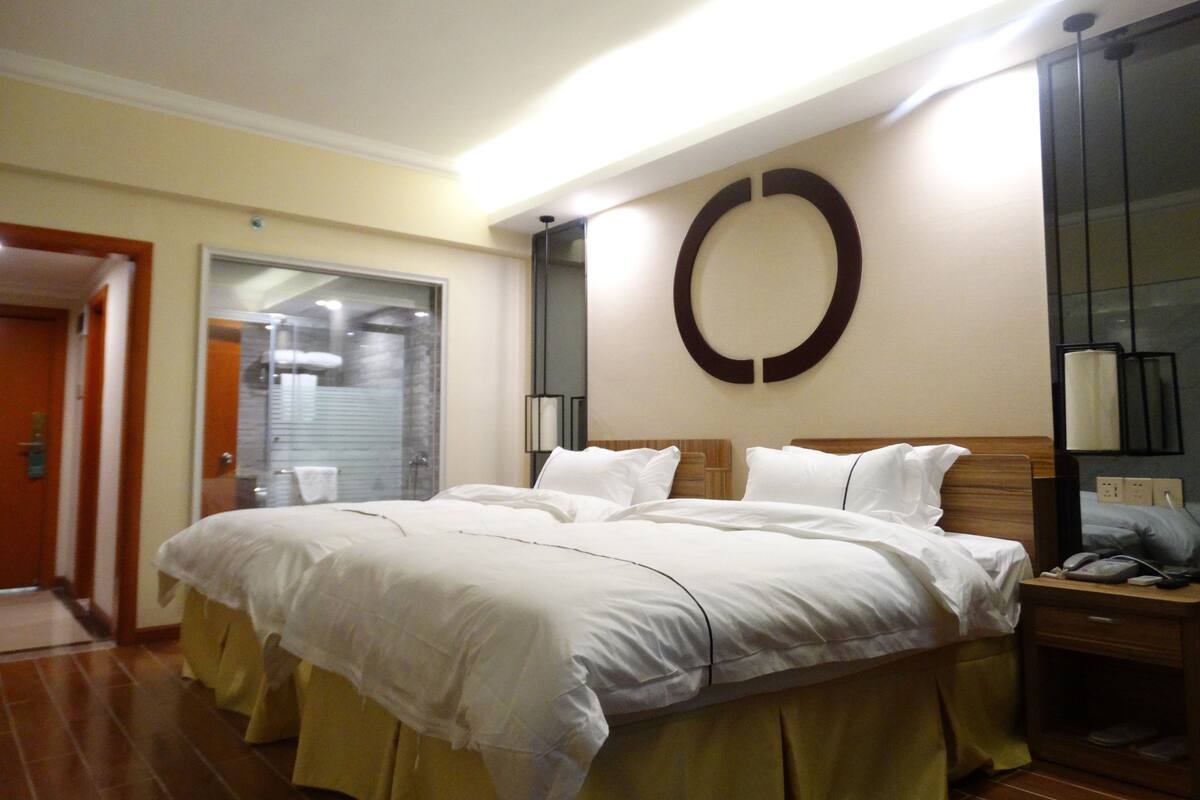 A hotel room with a large bed, a bedside table with a phone, and a mirror on the wall.