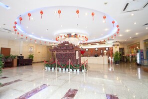 A hotel lobby with a reception desk, red lanterns, potted plants, and a marble floor. - Pengda Hotel Guangzhou (Guangzhou)