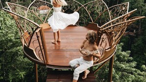 A wooden deck with a metal railing, surrounded by lush greenery and palm trees. - Villa Cella Bella (Ubud)