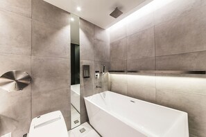 Une salle de bain moderne avec une grande baignoire, des toilettes et un espace douche.