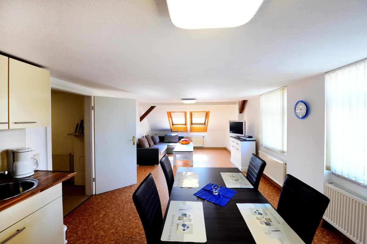 Ein modernes Hotelzimmer mit Essbereich, Küchenzeile und Wohnbereich.