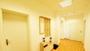 Un couloir avec un plancher en bois, un miroir, une armoire en bois et un tapis noir.