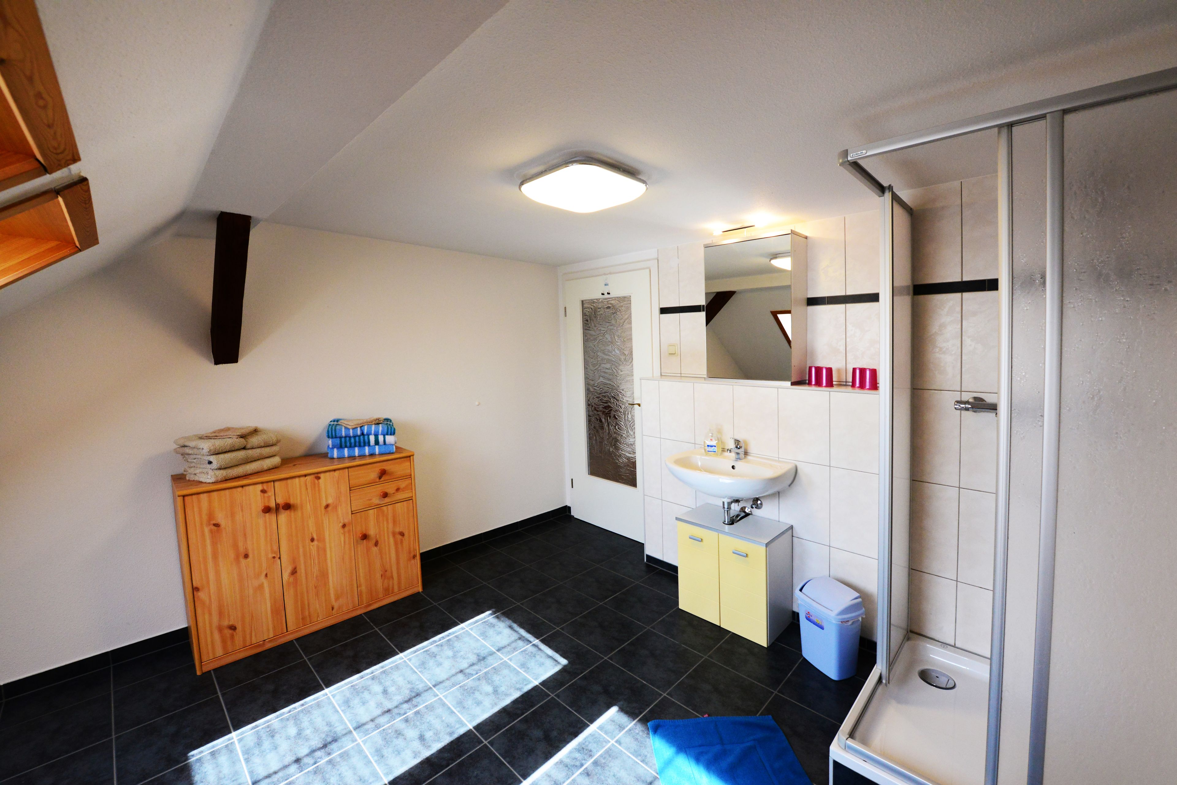 Une salle de bain avec un meuble en bois, un lavabo, un miroir et une douche.