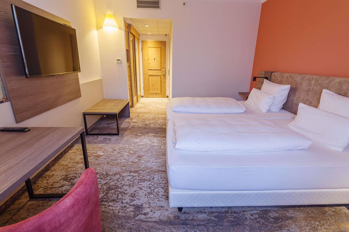 Une chambre d’hôtel comprenant un lit, un bureau, une télévision et une porte donnant sur une autre pièce.