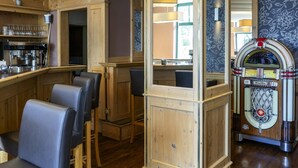 Eine Bar mit Holztischen, einem Jukebox und einer Kaffeemaschine.