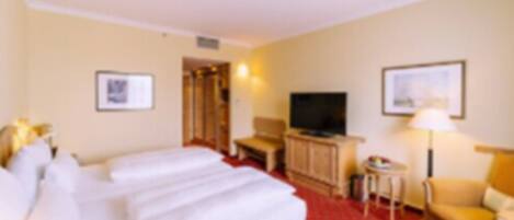 A hotel room with a bed, a television, a desk, and a chair.