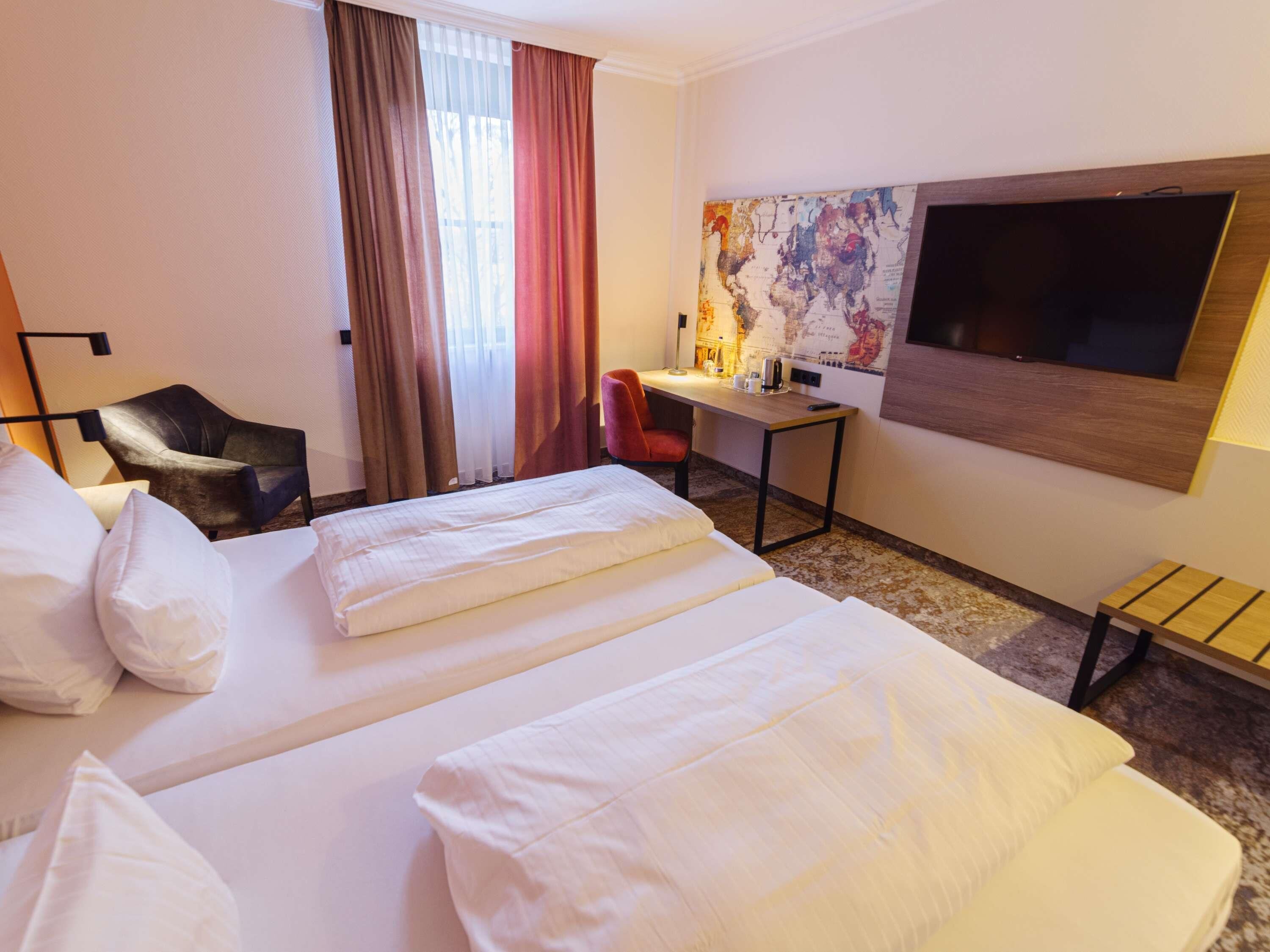 Een hotelkamer met twee bedden, een bureau, een stoel, een televisie en een kaart aan de muur.