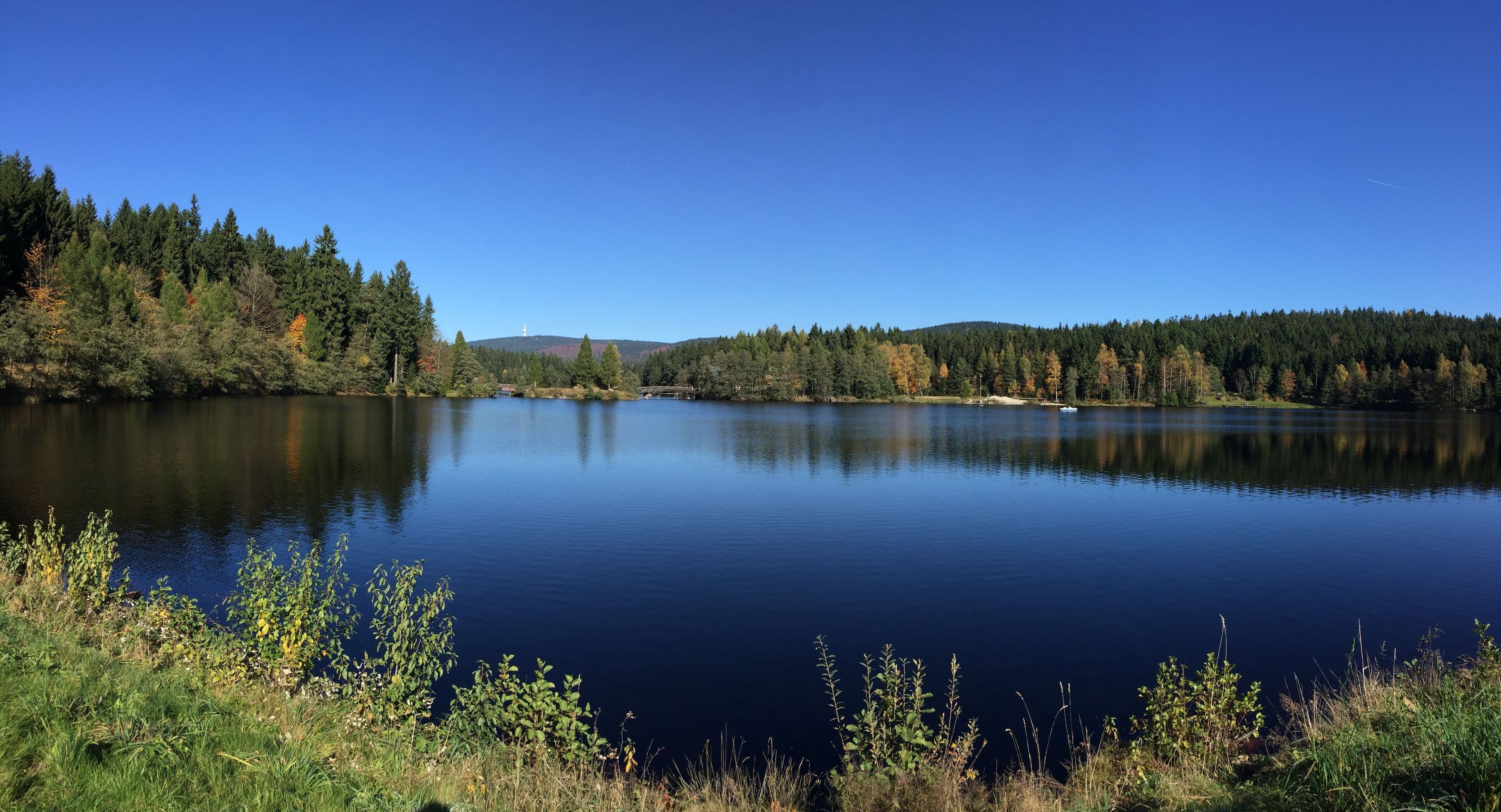 Um lago tranquilo rodeado por floresta densa e colinas.