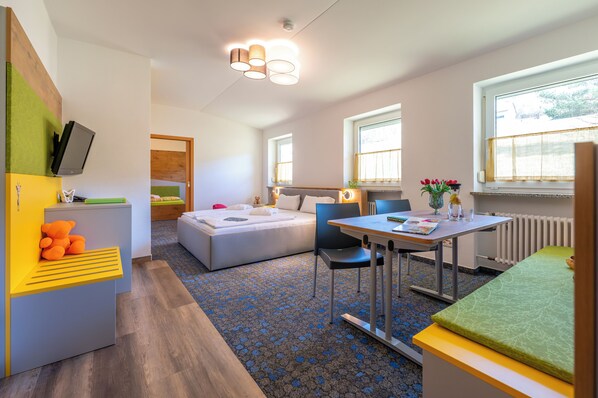 A modern hotel room with a bed, a desk, a chair, a TV, and a window. - Familotel Familienklub Krug (Warmensteinach)