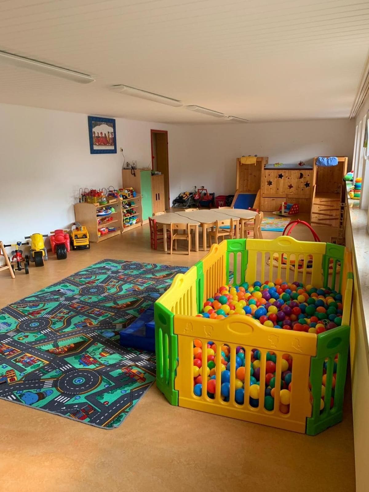 A playroom with a ball pit, a patterned rug, and a wooden playhouse.