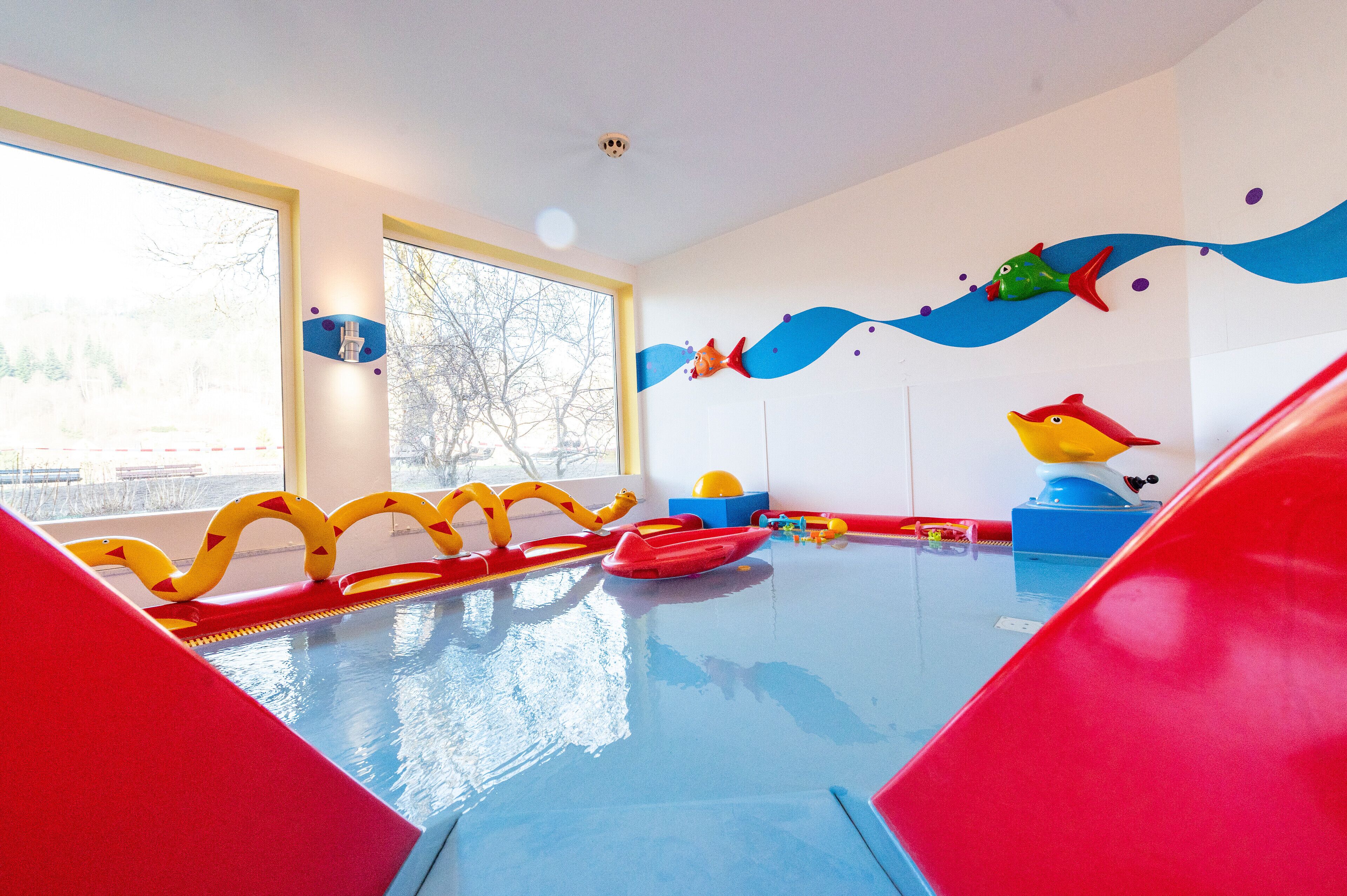 A children's play area with a pool, slides, and colorful decorations.
