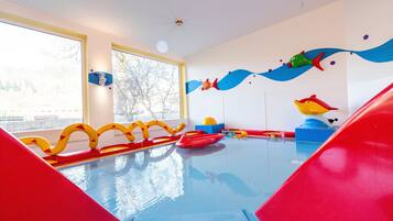 A children's play area with a pool, slides, and colorful decorations.