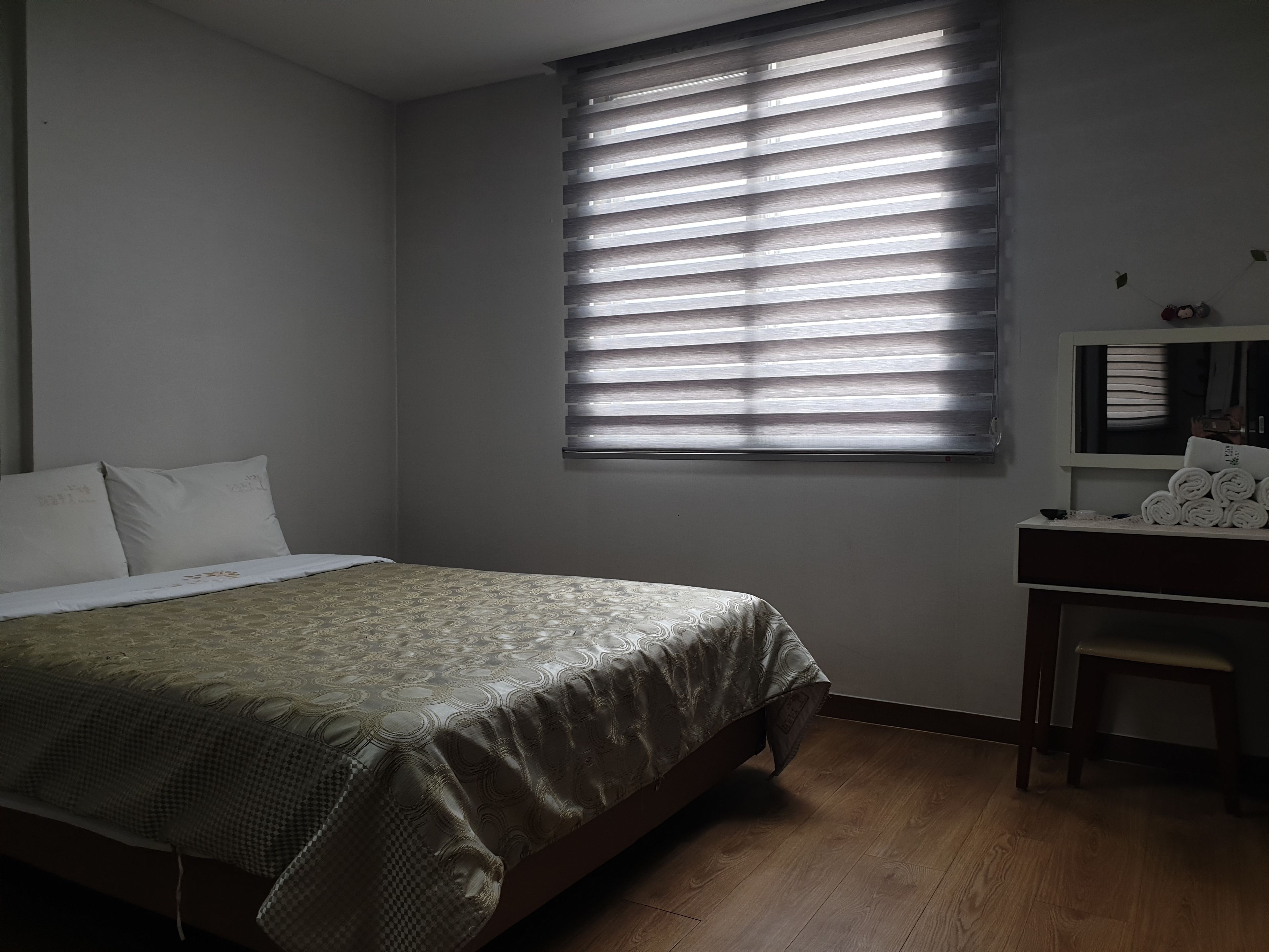 Un dormitorio con cama, escritorio y ventana con persianas.