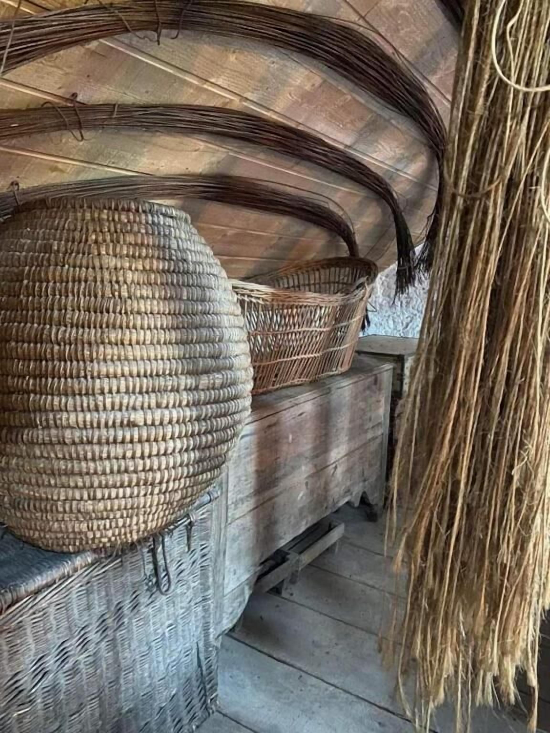 Una habitación rústica con techo curvo, una cesta tejida y un taburete de mimbre.