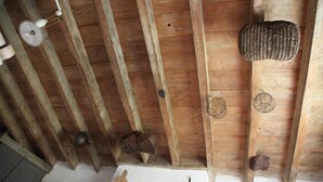 A wooden ceiling with exposed beams, a woven basket, and a hanging light fixture. - Gîte Le Porteau Enchanteur (Sarzay)