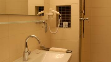 A modern bathroom with a sink, mirror, and shower.