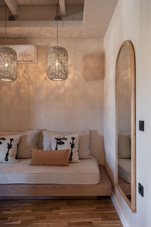 A modern living room with a sofa, decorative pillows, hanging lights, and a large mirror.