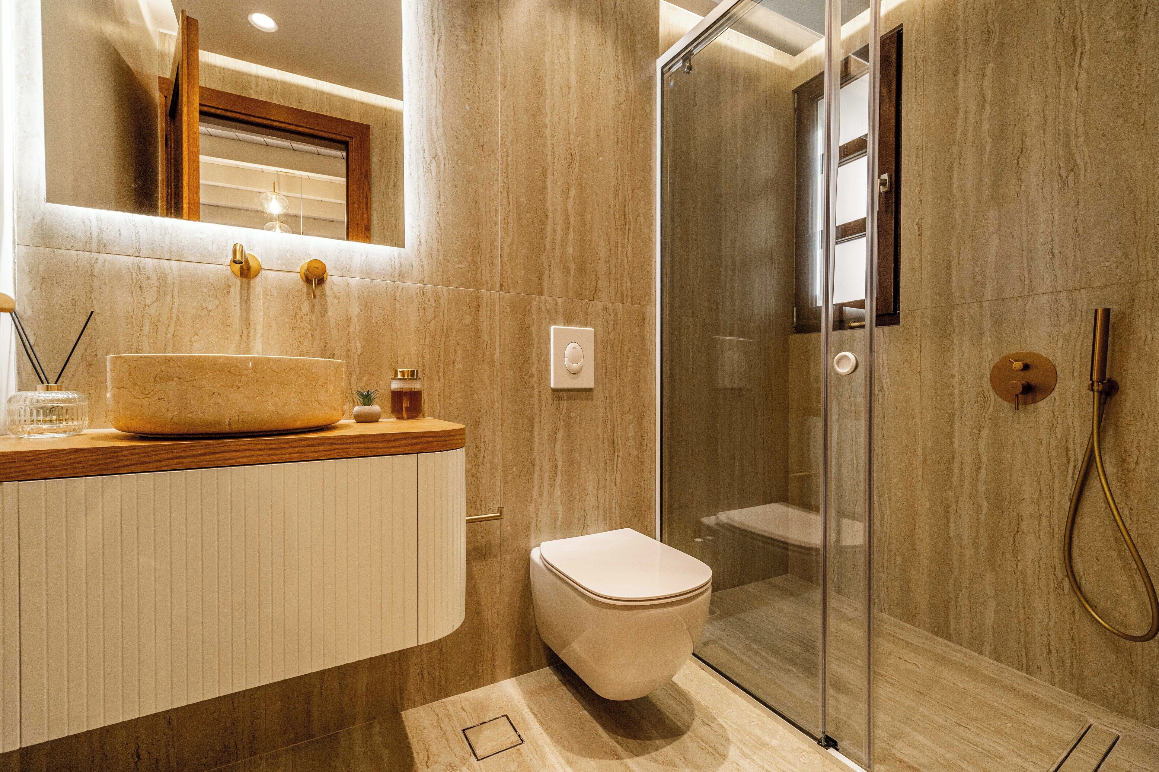 Un baño moderno con un lavamanos grande, un inodoro y una zona de ducha con mampara de vidrio.