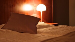 A bed with a pillow and a bedside lamp in a room with wooden paneling. - Hotel Zittauer Hof (Zittau)