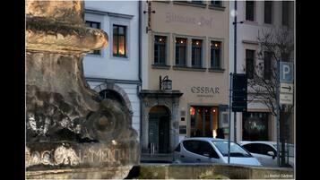 Un edificio con un cartel que indica 'Bittauer Hof' y 'ESSBAR', señalando un restaurante. Hay un cartel de estacionamiento con una flecha apuntando a la derecha.