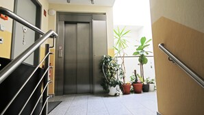A hotel lobby with a staircase, a closed elevator, and potted plants. - Hotel Zittauer Hof (Zittau)